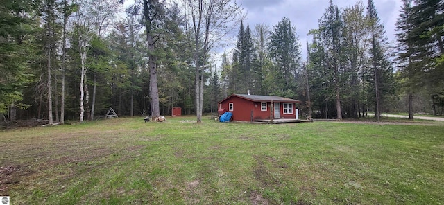 6031 Collins Rd, Onaway, MI 49765 - view of green lawn featuring a wooded view and an outbuilding