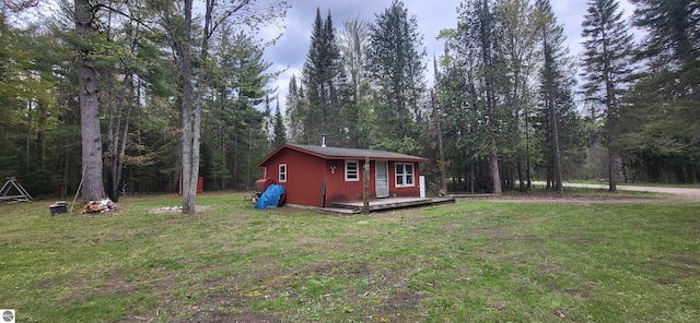 6031 Collins Rd, Onaway, MI 49765 - view of side of home with a lawn, an outdoor structure, and a view of trees