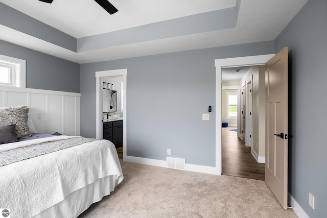 11964 E Shaker Trl, Suttons Bay, MI 49682 - bedroom with carpet flooring, connected bathroom, baseboards, ceiling fan, and a tray ceiling