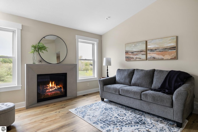 11964 E Shaker Trl, Suttons Bay, MI 49682 - living room with a glass covered fireplace, light wood finished floors, vaulted ceiling, and baseboards