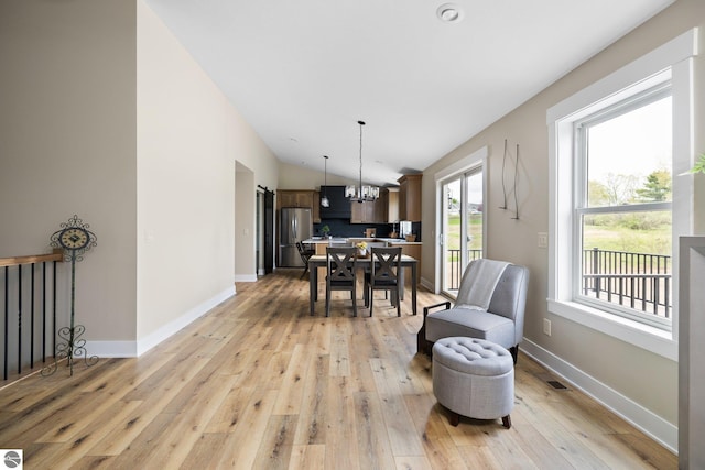 11964 E Shaker Trl, Suttons Bay, MI 49682 - dining space with light wood-type flooring, lofted ceiling, a chandelier, and baseboards