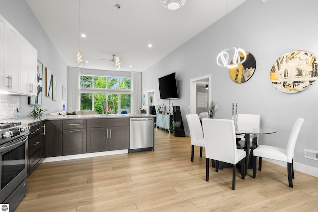 8906A Manhattan N Unit A, Traverse City, MI 49685 - kitchen featuring stainless steel appliances, a peninsula, white cabinetry, open floor plan, and light wood-style flooring