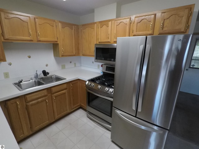 2118 E Lake Mitchell Dr, Cadillac, MI 49601 - kitchen with stainless steel appliances, a sink, light countertops, and brown cabinetry