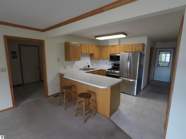 2118 E Lake Mitchell Dr, Cadillac, MI 49601 - kitchen with stainless steel appliances, a peninsula, a sink, light countertops, and a breakfast bar