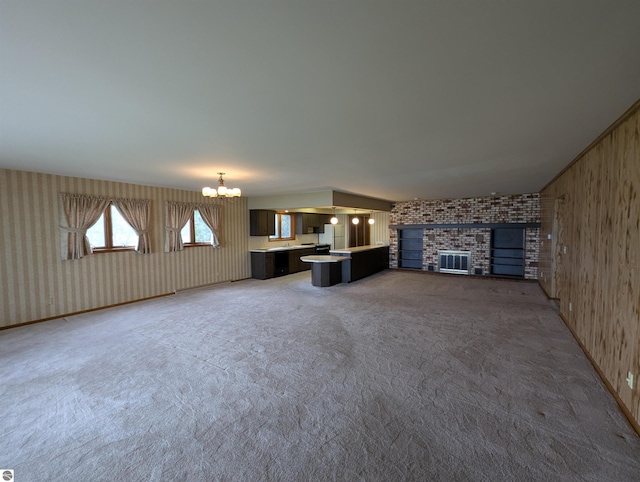 1082 S Sixth St, Au Gres, MI 48703 - unfurnished living room with a chandelier, carpet floors, and a brick fireplace