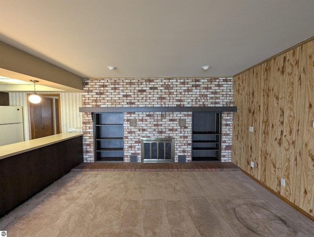 1082 S Sixth St, Au Gres, MI 48703 - unfurnished living room featuring wooden walls, a brick fireplace, and carpet