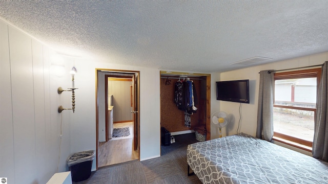 605 Cedar Ave, Houghton Lake, MI 48651 - bedroom featuring a textured ceiling, two closets, and dark carpet