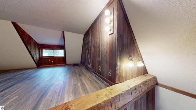 605 Cedar Ave, Houghton Lake, MI 48651 - stairway featuring wood finished floors, wooden walls, a textured ceiling, and a textured wall