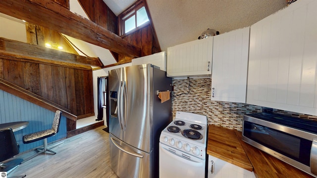 605 Cedar Ave, Houghton Lake, MI 48651 - kitchen with stainless steel appliances, backsplash, light wood finished floors, vaulted ceiling, and white cabinetry