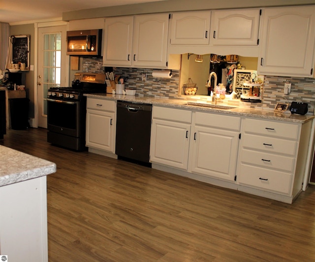 3690 Rau Rd, West Branch, MI 48661 - kitchen with stainless steel appliances, a sink, white cabinetry, tasteful backsplash, and wood finished floors