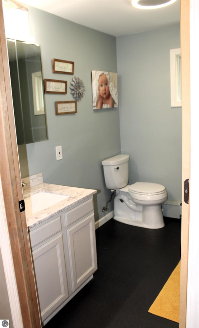 3690 Rau Rd, West Branch, MI 48661 - bathroom featuring toilet, baseboards, vanity, and a baseboard heating unit