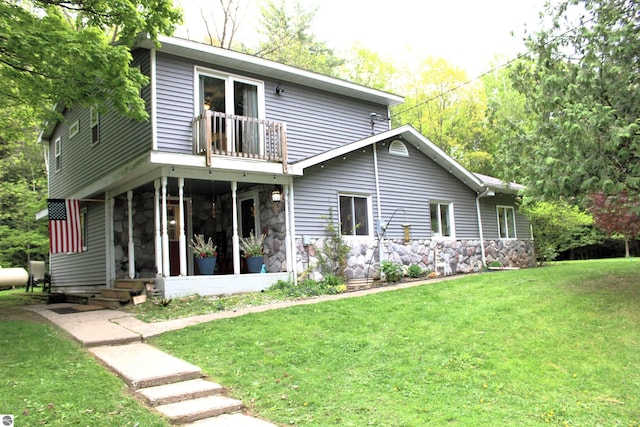 3690 Rau Rd, West Branch, MI 48661 - rear view of house featuring a balcony, stone siding, a sunroom, and a yard