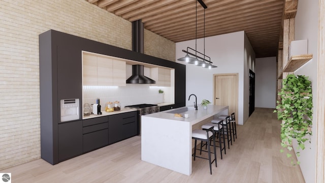 109 E Front St # 213, Traverse City, MI 49684 - kitchen featuring wall chimney exhaust hood, a sink, modern cabinets, a kitchen bar, and decorative light fixtures