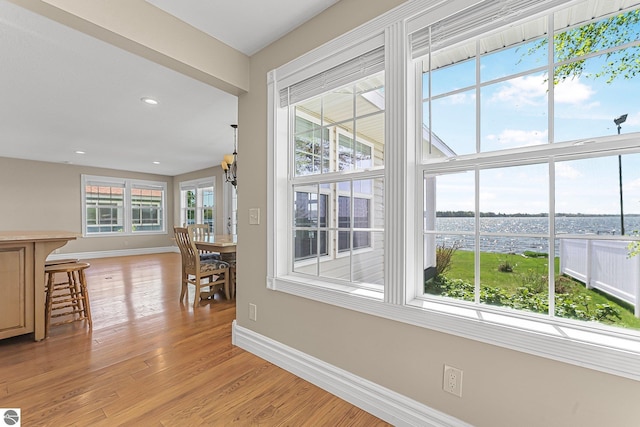 3151 W Lake Mitchell Dr, Cadillac, MI 49601 - unfurnished dining area with baseboards, light wood-type flooring, a water view, and recessed lighting