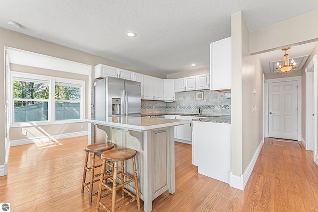 3151 W Lake Mitchell Dr, Cadillac, MI 49601 - kitchen featuring baseboards, a chandelier, light wood-type flooring, a kitchen bar, and a textured ceiling