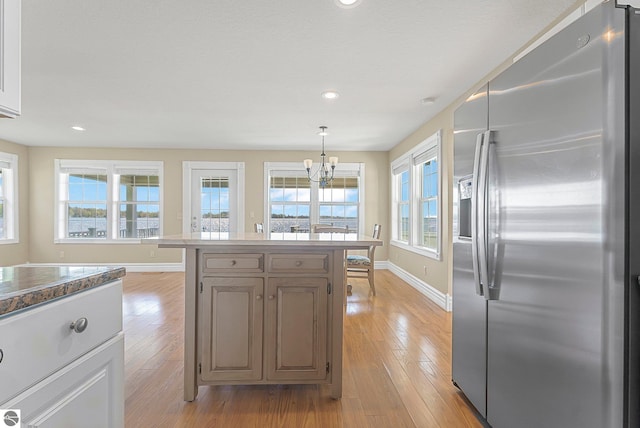 3151 W Lake Mitchell Dr, Cadillac, MI 49601 - kitchen with stainless steel fridge, a chandelier, baseboards, light wood-type flooring, and recessed lighting