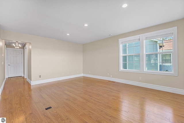 3151 W Lake Mitchell Dr, Cadillac, MI 49601 - spare room with a chandelier, baseboards, light wood-style floors, and recessed lighting