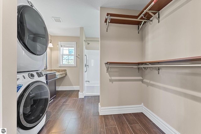3151 W Lake Mitchell Dr, Cadillac, MI 49601 - washroom with stacked washing machine and dryer, baseboards, and dark wood-type flooring