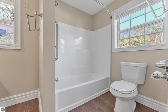 3151 W Lake Mitchell Dr, Cadillac, MI 49601 - bathroom with baseboards, toilet, bathing tub / shower combination, and wood finished floors