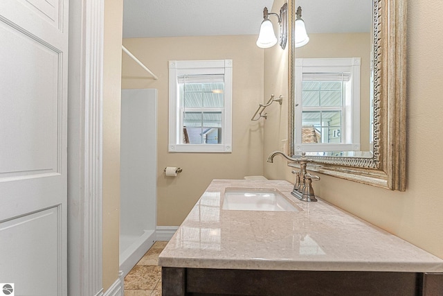 3151 W Lake Mitchell Dr, Cadillac, MI 49601 - full bathroom with vanity, walk in shower, healthy amount of natural light, and baseboards