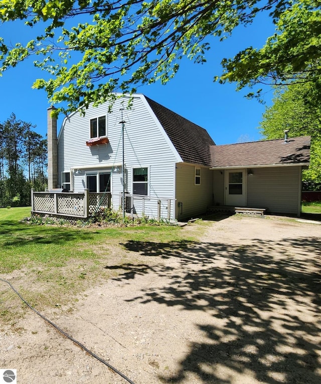 6878 Boss Rd, Ellsworth, MI 49727 - back of house featuring a chimney, a lawn, and a wooden deck
