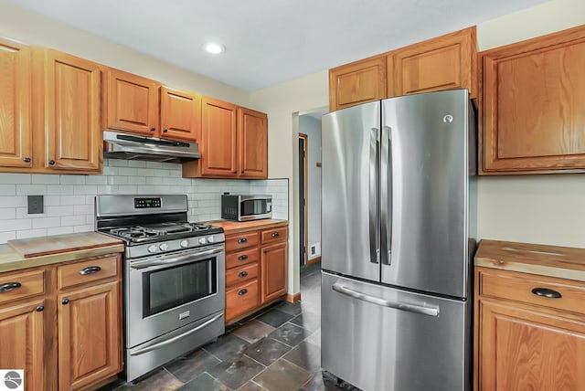 8281 M-66, Fife Lake, MI 49633 - kitchen with appliances with stainless steel finishes, under cabinet range hood, backsplash, recessed lighting, and brown cabinets