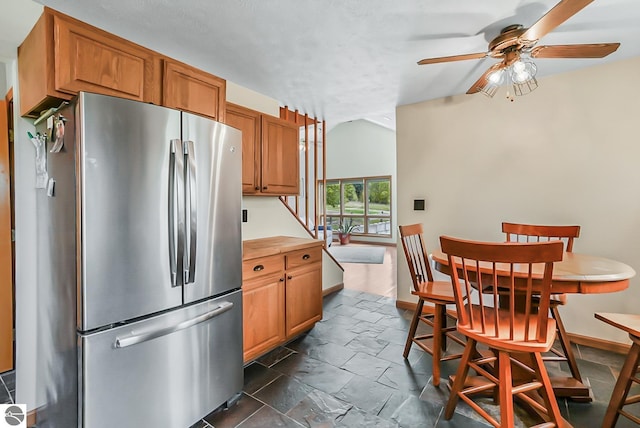 8281 M-66, Fife Lake, MI 49633 - kitchen featuring freestanding refrigerator, ceiling fan, brown cabinetry, dark stone finish flooring, and baseboards