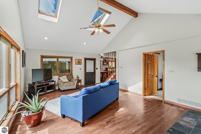 8281 M-66, Fife Lake, MI 49633 - living area featuring a skylight, high vaulted ceiling, ceiling fan, beam ceiling, and wood finished floors