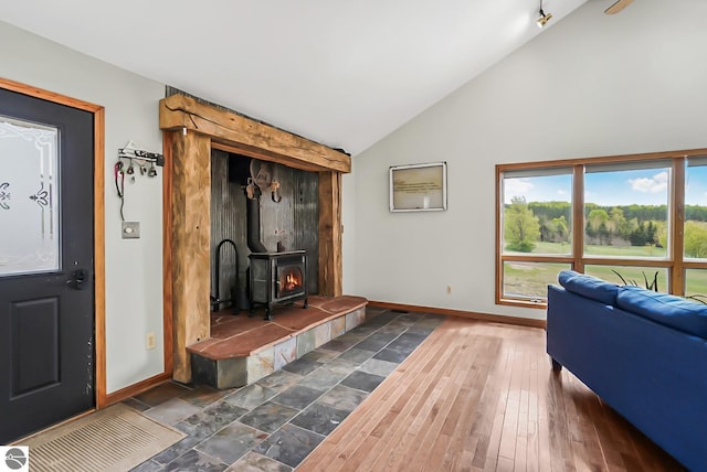 8281 M-66, Fife Lake, MI 49633 - living room with baseboards, a wood stove, and high vaulted ceiling