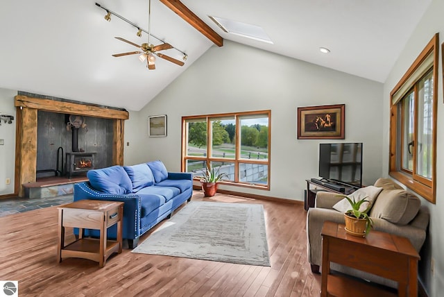 8281 M-66, Fife Lake, MI 49633 - living area with a wood stove, beamed ceiling, ceiling fan, a skylight, and wood finished floors