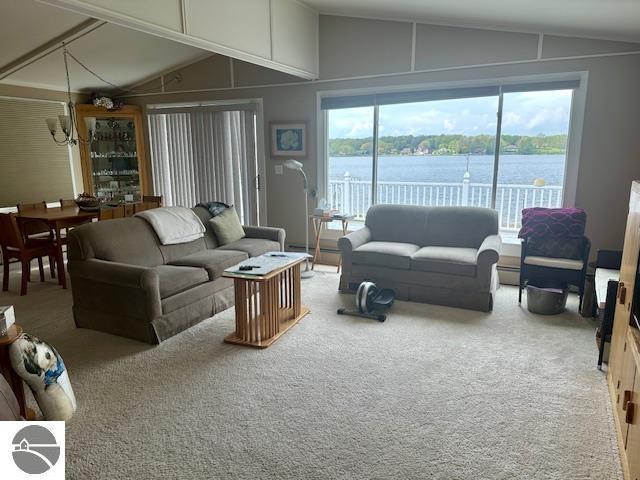 1094 Fairway Dr, Lake Isabella, MI 48893 - living room featuring vaulted ceiling, carpet, a baseboard heating unit, and a water view
