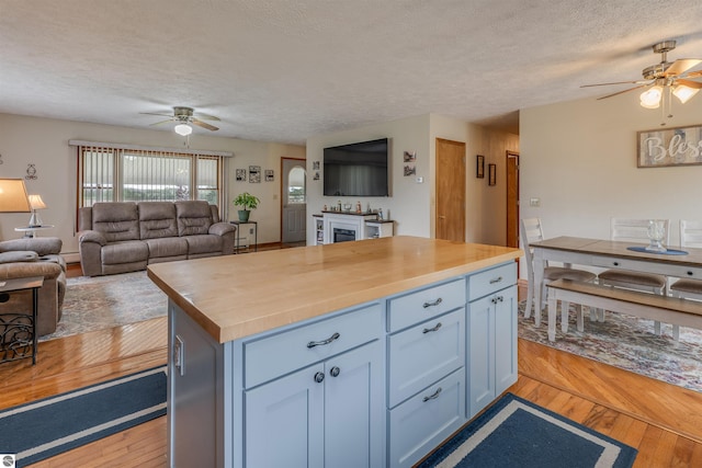 605 E M-55, West Branch, MI 48661 - kitchen featuring a ceiling fan, a textured ceiling, open floor plan, light wood-style floors, and wood counters