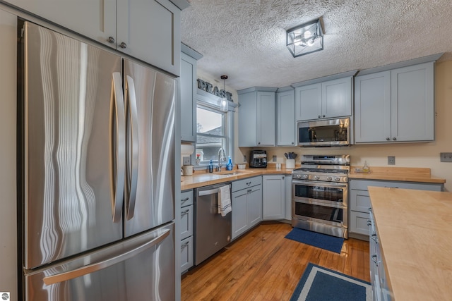 605 E M-55, West Branch, MI 48661 - kitchen featuring wood counters, stainless steel appliances, a sink, light wood finished floors, and gray cabinets