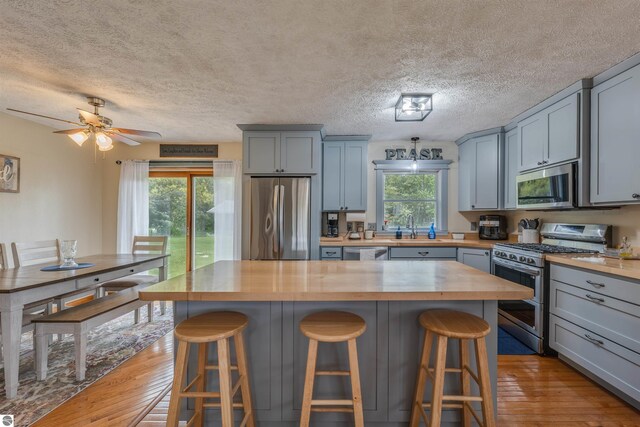 605 E M-55, West Branch, MI 48661 - kitchen featuring wood counters, stainless steel appliances, light wood-type flooring, gray cabinets, and a textured ceiling