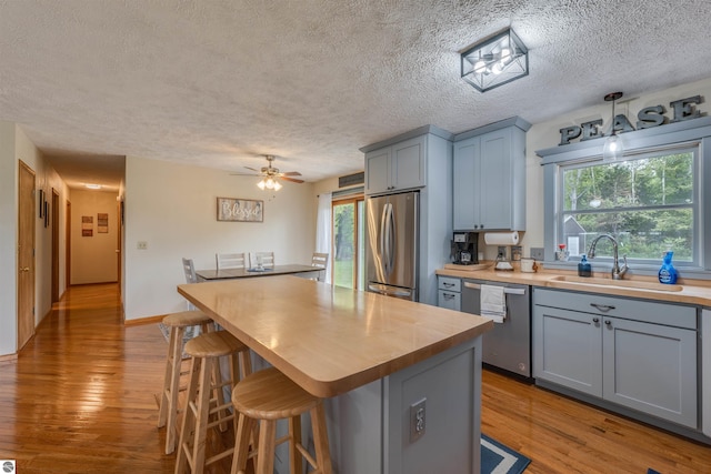 605 E M-55, West Branch, MI 48661 - kitchen with stainless steel appliances, a sink, wood counters, light wood finished floors, and a textured ceiling