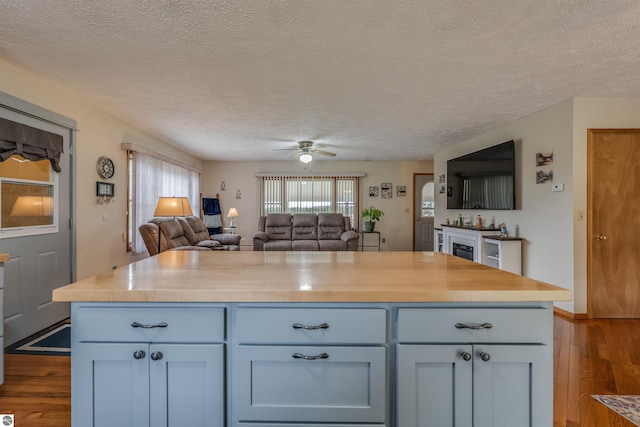 605 E M-55, West Branch, MI 48661 - kitchen featuring dark wood-style floors, a textured ceiling, open floor plan, ceiling fan, and wooden counters