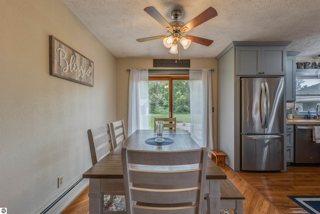 605 E M-55, West Branch, MI 48661 - dining area featuring wood finished floors, a textured ceiling, ceiling fan, and baseboard heating