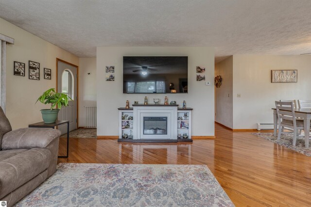 605 E M-55, West Branch, MI 48661 - living area with wood finished floors, a textured ceiling, radiator, baseboards, and a baseboard radiator