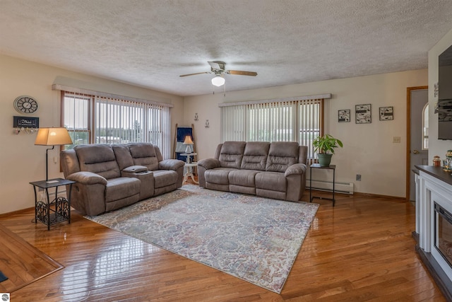 605 E M-55, West Branch, MI 48661 - living area featuring a baseboard heating unit, a ceiling fan, hardwood / wood-style floors, a textured ceiling, and baseboards