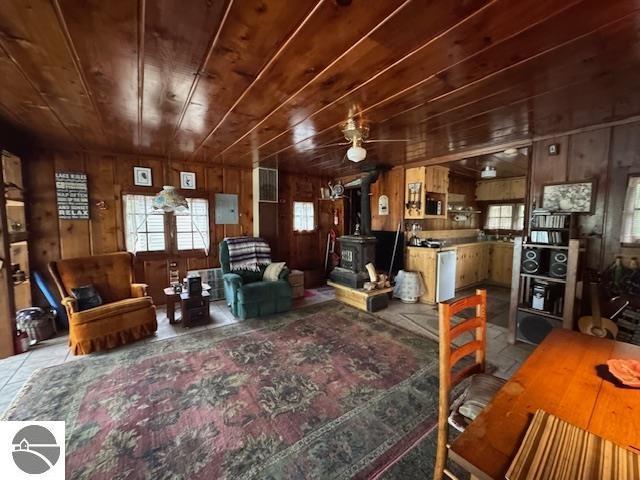 951 Lake Dr, Harrison, MI 48625 - living room with a wood stove, plenty of natural light, wooden walls, and wood ceiling