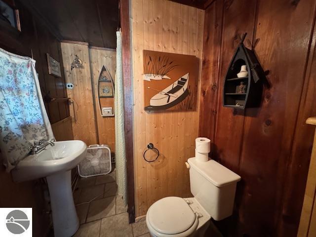 951 Lake Dr, Harrison, MI 48625 - half bath featuring wood walls, toilet, and tile patterned floors
