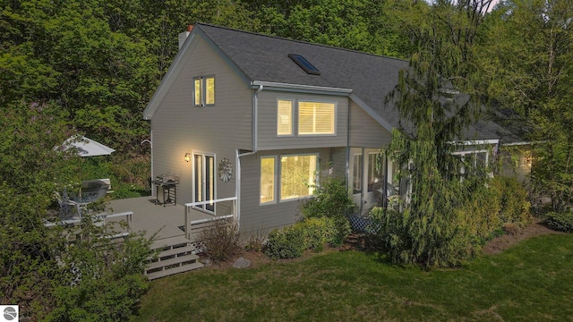 1321 N Manitou Trl, Leland, MI 49654 - view of front of home featuring a shingled roof, a front yard, and a wooden deck