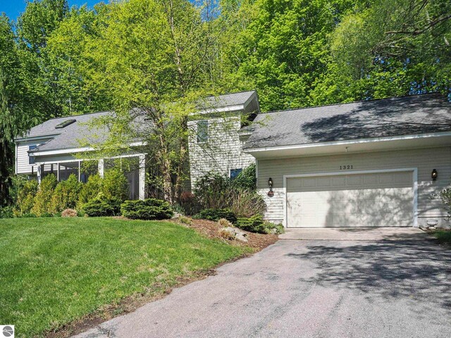 1321 N Manitou Trl, Leland, MI 49654 - view of front of property with asphalt driveway, an attached garage, and a front lawn