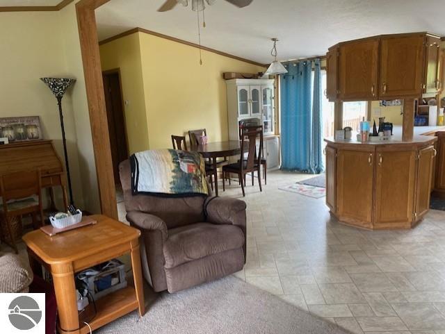 10559 Rosted Rd, Lake City, MI 49651 - kitchen with ceiling fan, crown molding, brown cabinets, decorative light fixtures, and light stone finish flooring