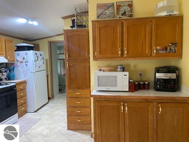 10559 Rosted Rd, Lake City, MI 49651 - kitchen featuring white appliances, brown cabinetry, light countertops, crown molding, and extractor fan
