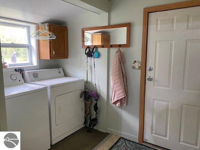10559 Rosted Rd, Lake City, MI 49651 - laundry area with washer and dryer, cabinet space, baseboards, and light tile patterned floors