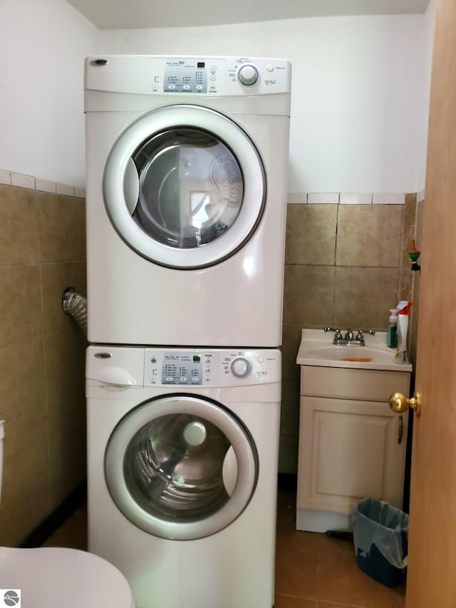 1148 Horseshoe Dr, Alger, MI 48610 - laundry area with stacked washing machine and dryer, tile walls, tile patterned flooring, and wainscoting