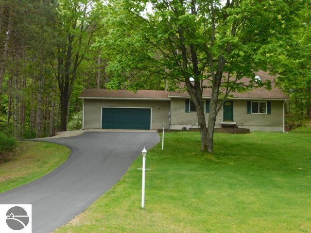 12149 Cabin Ln, Rapid City, MI 49676 - ranch-style home with driveway, an attached garage, and a front yard