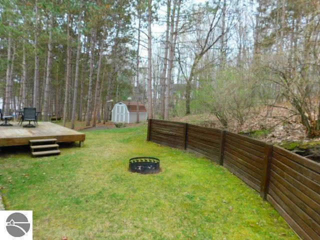 12149 Cabin Ln, Rapid City, MI 49676 - view of yard with a wooden deck and a fire pit