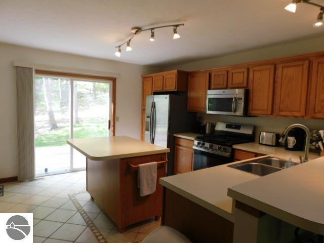 12149 Cabin Ln, Rapid City, MI 49676 - kitchen featuring appliances with stainless steel finishes, brown cabinets, light countertops, and light tile patterned flooring